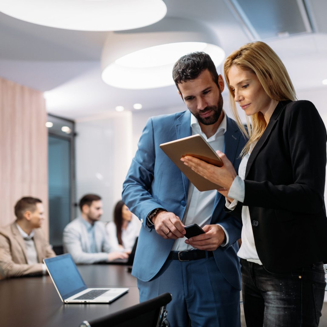 Businesspeople discussing while using digital tablet in office together